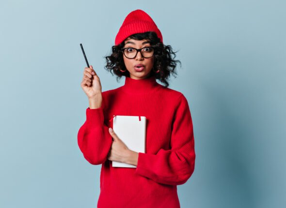 Shocked international student holding pen and notebook. Amazed mixed race girl posing with planner
